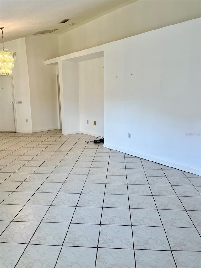 spare room featuring light tile patterned flooring and an inviting chandelier