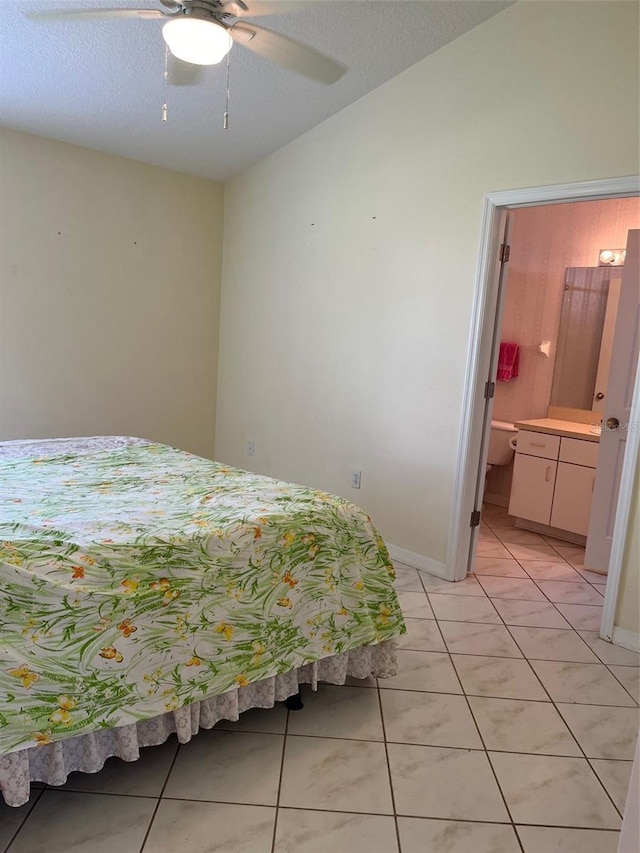 bedroom featuring a textured ceiling, light tile patterned floors, connected bathroom, and ceiling fan