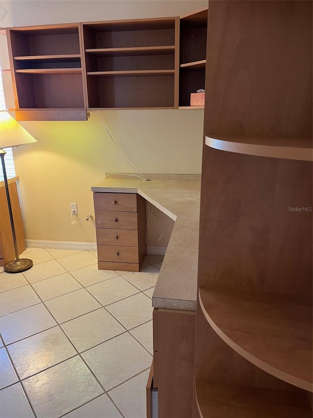 unfurnished office featuring built in desk and light tile patterned floors