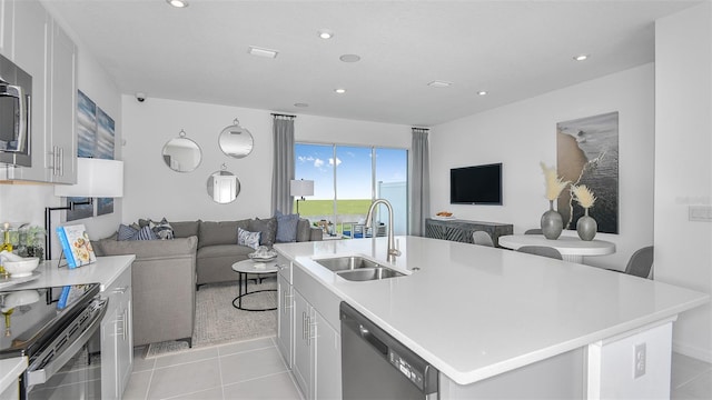 kitchen featuring light tile patterned floors, white cabinetry, a kitchen island with sink, stainless steel appliances, and sink