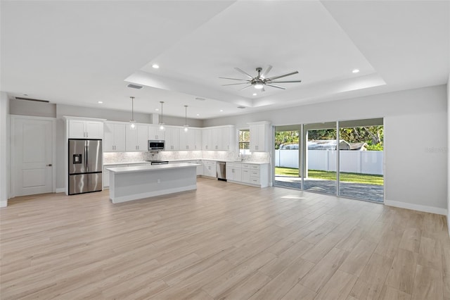 kitchen with appliances with stainless steel finishes, hanging light fixtures, light wood-type flooring, and white cabinetry