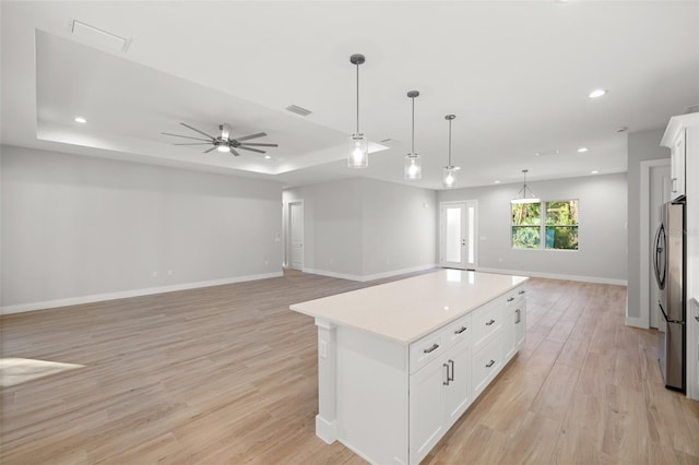 kitchen featuring stainless steel fridge, a center island, light wood-type flooring, and white cabinets