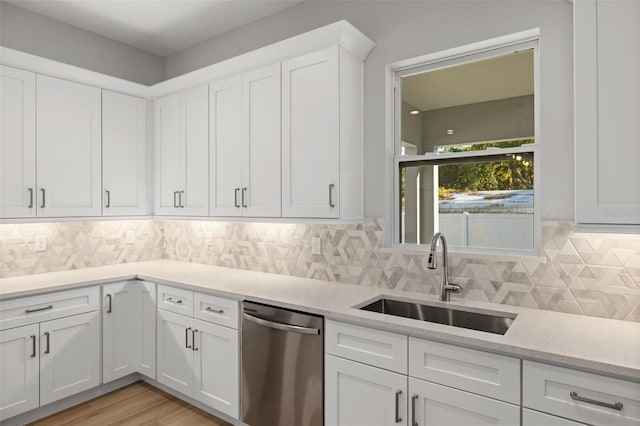 kitchen featuring white cabinets, stainless steel dishwasher, sink, and backsplash