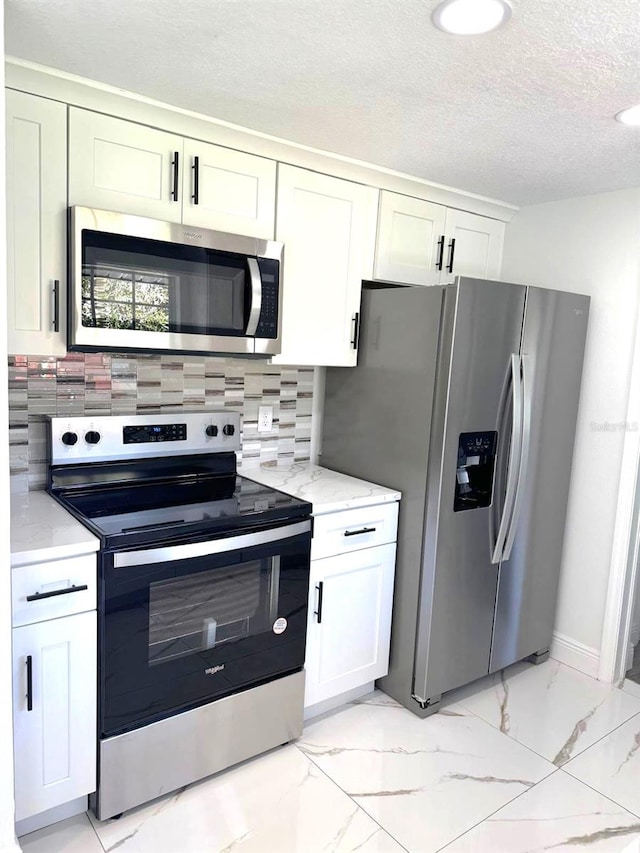 kitchen with appliances with stainless steel finishes, decorative backsplash, light stone counters, and white cabinetry