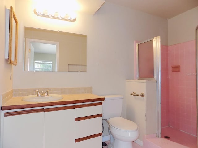 bathroom featuring toilet, vanity, and a tile shower