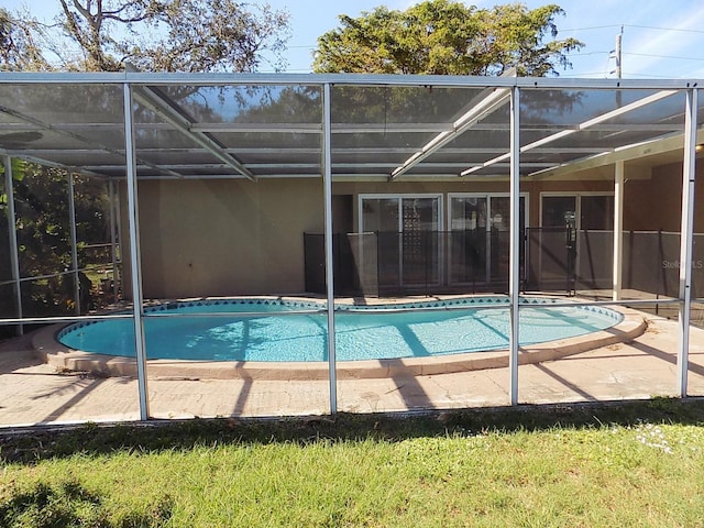 view of swimming pool featuring a patio and glass enclosure