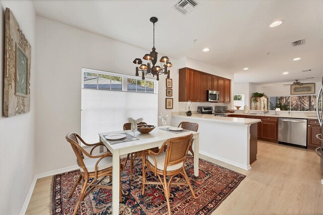 dining area with light wood-type flooring, a chandelier, and sink