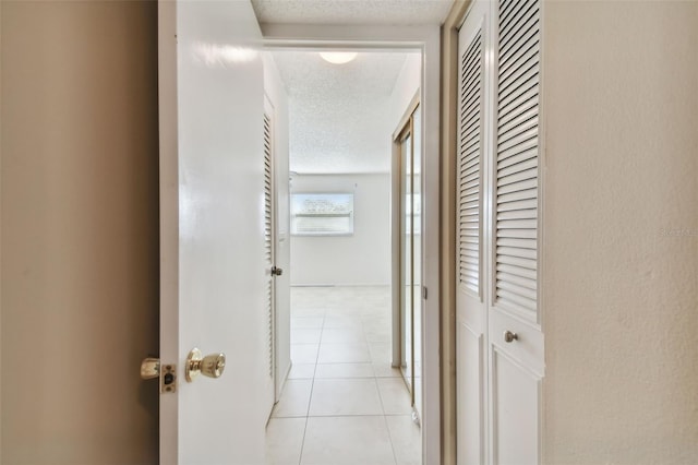 corridor featuring a textured ceiling and light tile patterned floors