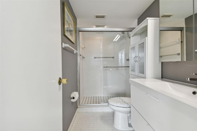 bathroom featuring toilet, vanity, tile patterned floors, and a shower with shower door