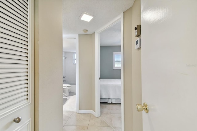 hallway with a textured ceiling and light tile patterned floors