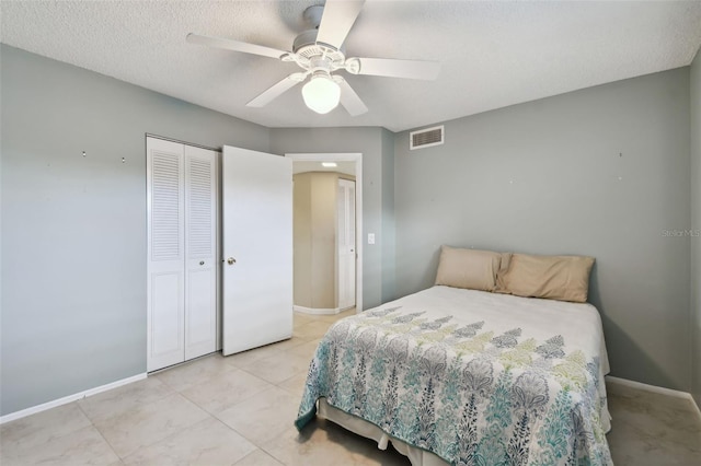 tiled bedroom with a textured ceiling, ceiling fan, and a closet