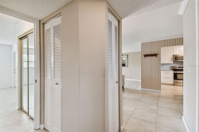 corridor featuring a textured ceiling and light tile patterned floors