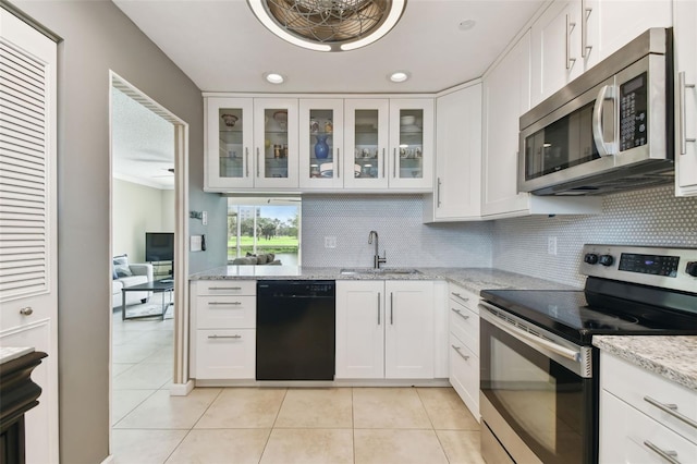 kitchen featuring light tile patterned flooring, stainless steel appliances, white cabinetry, light stone countertops, and sink