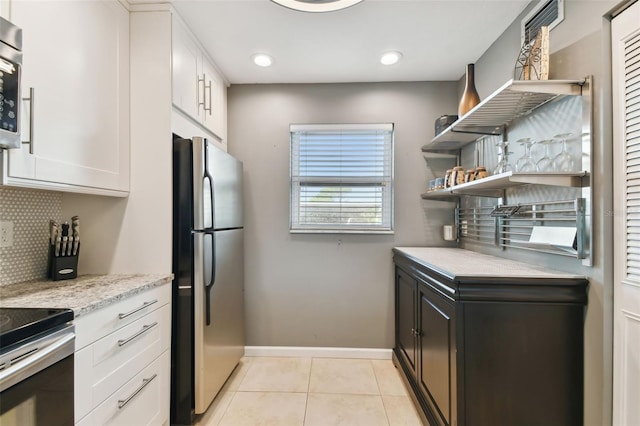 kitchen featuring light stone counters, white cabinets, decorative backsplash, light tile patterned flooring, and appliances with stainless steel finishes