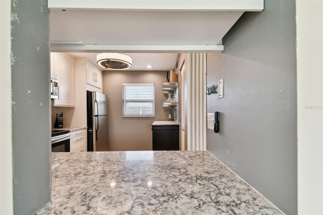 kitchen featuring light stone countertops, white cabinetry, and appliances with stainless steel finishes