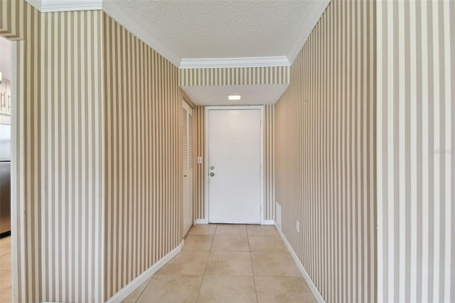 hall featuring a textured ceiling, ornamental molding, and light tile patterned floors