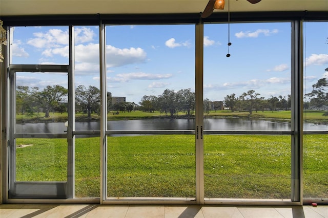 unfurnished sunroom featuring ceiling fan and a water view