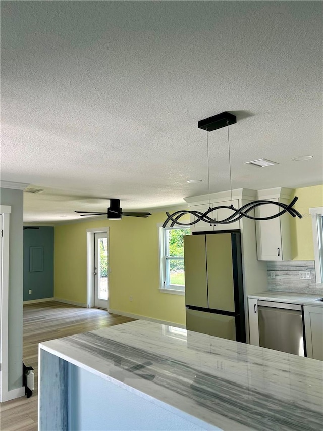 kitchen with stainless steel appliances, light hardwood / wood-style floors, hanging light fixtures, backsplash, and white cabinetry