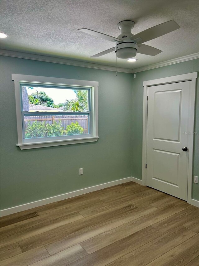 spare room featuring light hardwood / wood-style floors, ceiling fan, a textured ceiling, and crown molding