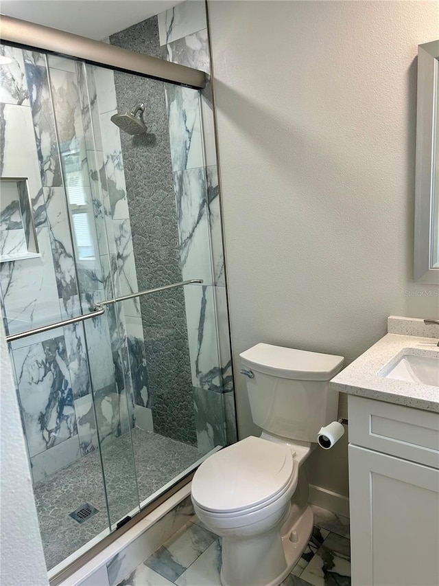 bathroom featuring toilet, vanity, and a shower with shower door