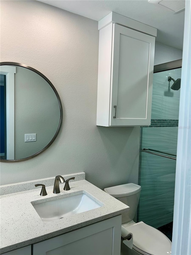 bathroom with toilet, vanity, and walk in shower