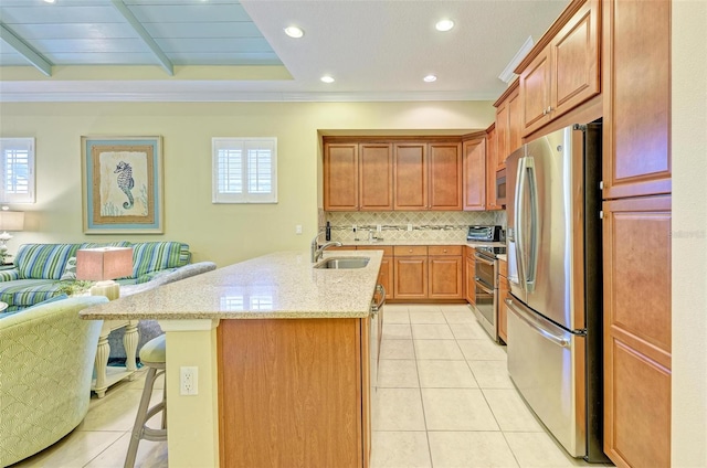 kitchen with tasteful backsplash, an island with sink, a kitchen breakfast bar, sink, and stainless steel appliances