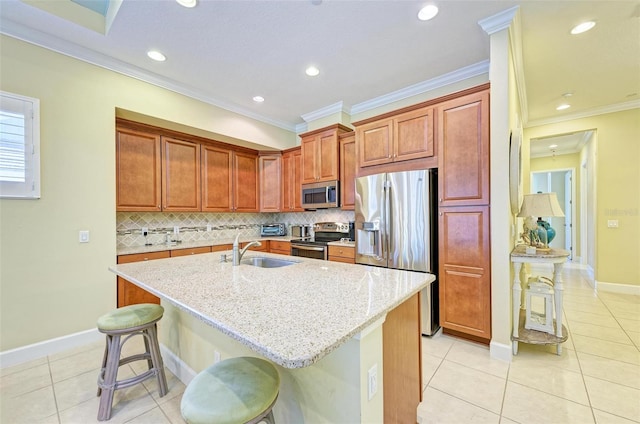 kitchen featuring a kitchen island with sink, a kitchen breakfast bar, stainless steel appliances, sink, and light stone countertops