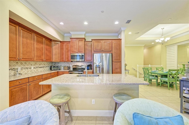 kitchen with crown molding, stainless steel appliances, and a kitchen island with sink