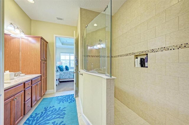 bathroom with vanity, a tile shower, and tile patterned flooring