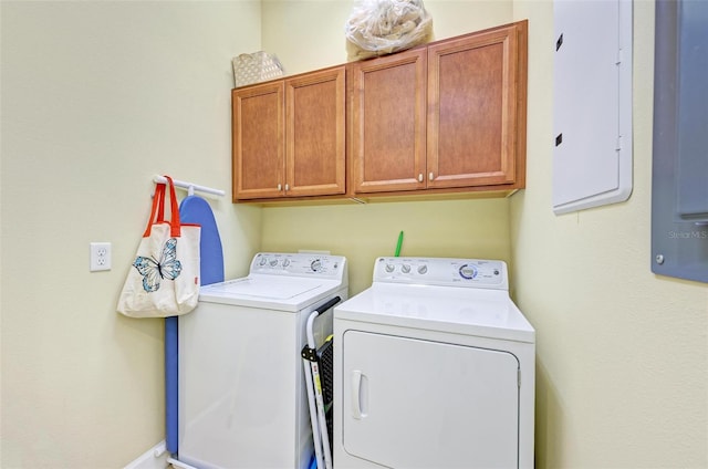 clothes washing area featuring electric panel, separate washer and dryer, and cabinets