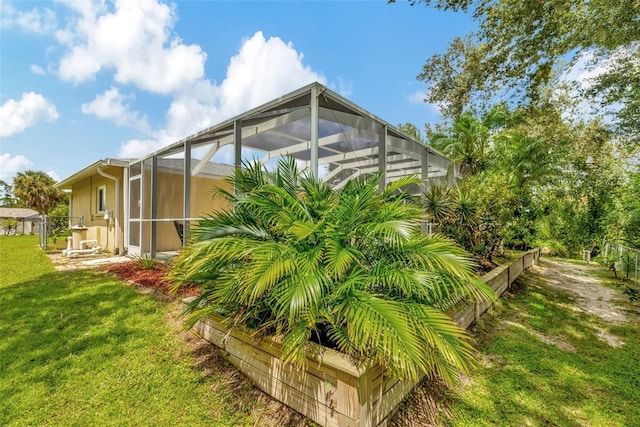 view of side of home with glass enclosure and a lawn