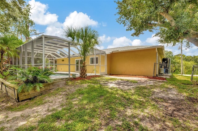 back of property with a lawn, a lanai, and a patio