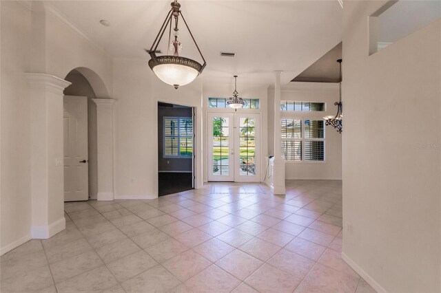 interior space featuring light tile patterned flooring, ornate columns, ornamental molding, and french doors