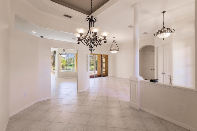 interior space featuring decorative columns, a tray ceiling, crown molding, and light tile patterned flooring