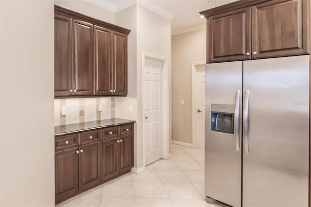 kitchen featuring dark stone countertops, stainless steel fridge, decorative backsplash, light tile patterned flooring, and ornamental molding