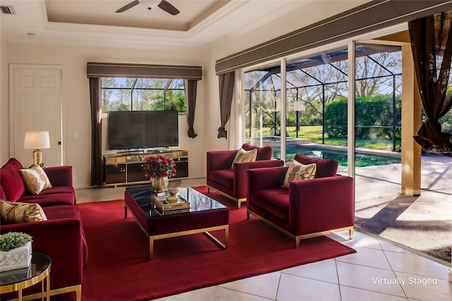 tiled living room featuring a raised ceiling, plenty of natural light, ornamental molding, and ceiling fan