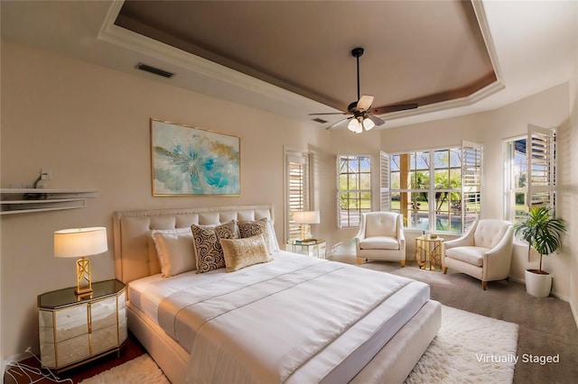 carpeted bedroom featuring ceiling fan and a raised ceiling