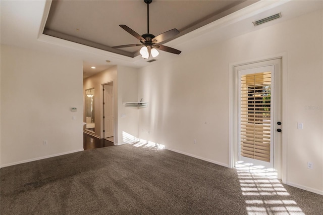 carpeted empty room featuring a raised ceiling and ceiling fan