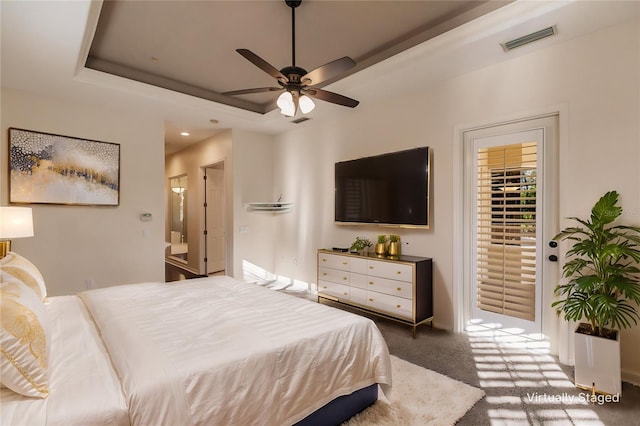 bedroom featuring dark colored carpet, ceiling fan, access to exterior, and a tray ceiling