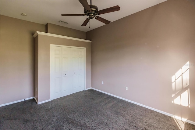 unfurnished bedroom with dark colored carpet, a closet, and ceiling fan