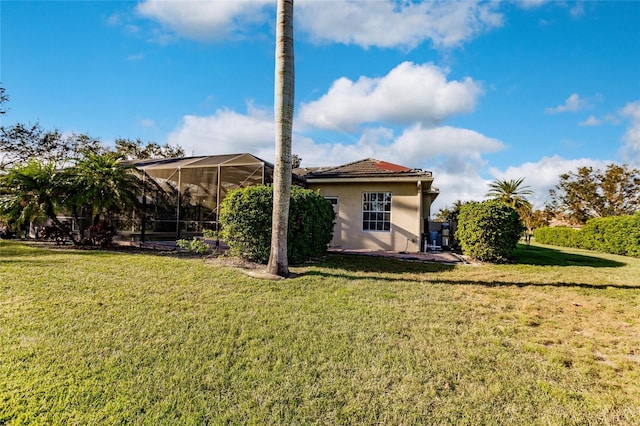 back of property featuring a lanai and a lawn