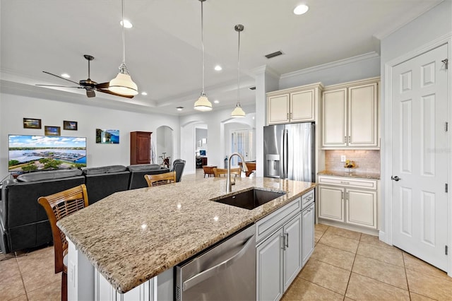 kitchen featuring stainless steel appliances, ceiling fan, sink, hanging light fixtures, and an island with sink