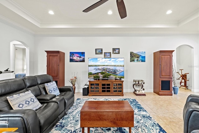 tiled living room with a tray ceiling, ceiling fan, and ornamental molding