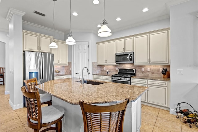 kitchen featuring a kitchen island with sink, sink, stainless steel appliances, and light stone counters