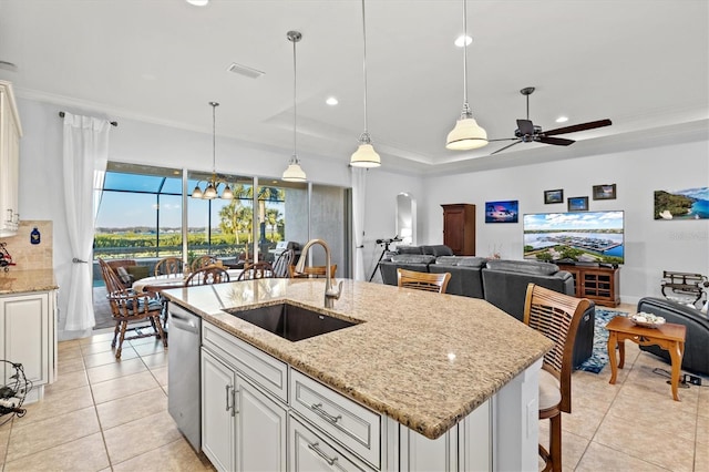 kitchen featuring a raised ceiling, dishwasher, sink, and decorative light fixtures