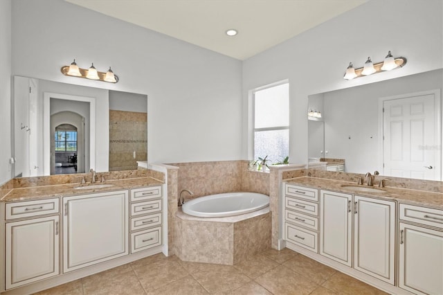 bathroom featuring vanity, a relaxing tiled tub, and tile patterned floors