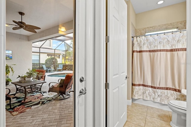 bathroom with toilet, tile patterned floors, ceiling fan, and shower / tub combo with curtain