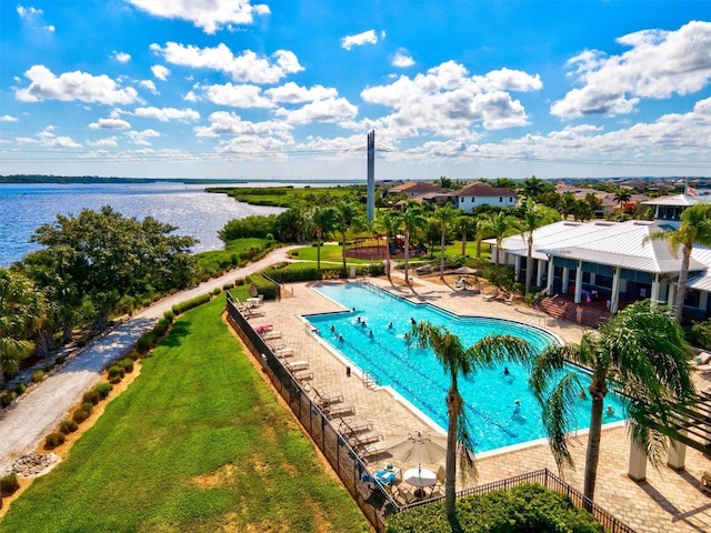 view of swimming pool featuring a lawn, a water view, and a patio