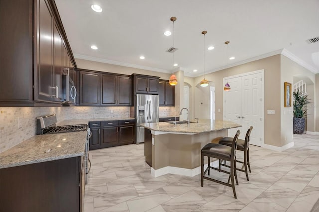 kitchen featuring pendant lighting, sink, backsplash, stainless steel appliances, and an island with sink