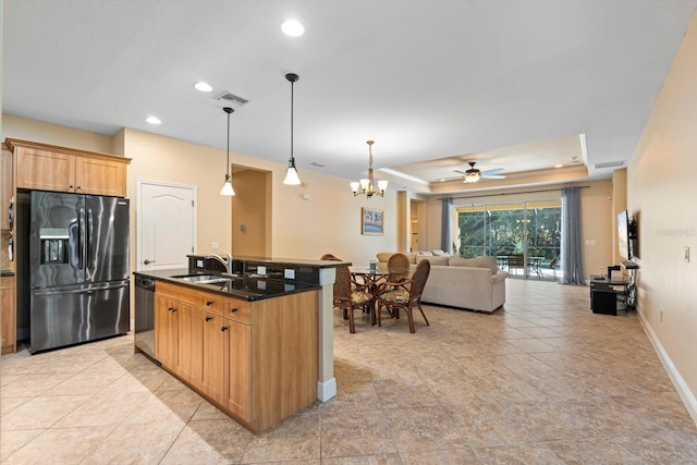 kitchen with hanging light fixtures, a center island with sink, sink, a raised ceiling, and appliances with stainless steel finishes